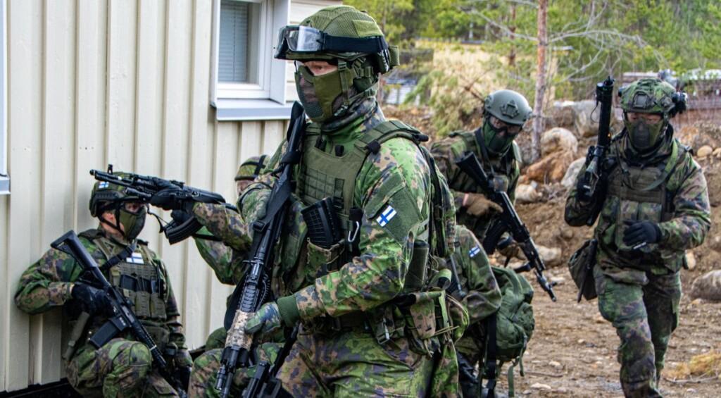 Maastoasuisia henkilöitä rakennuksen läheisyydessä harjoittelemassa airsoft-aseiden kanssa.